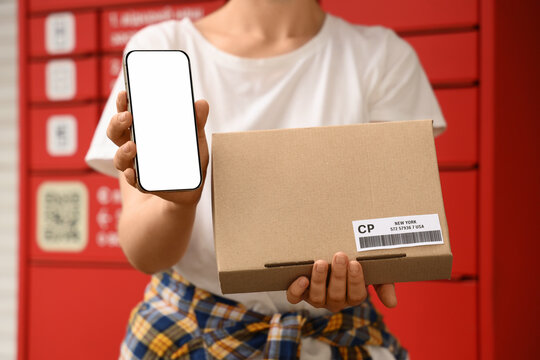 Package delivery and e-commerce tracking, person holding cardboard box and smartphone with blank screen at automated parcel locker for pickup service