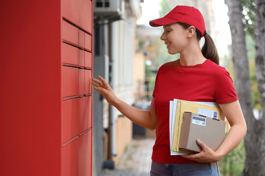 Logistics and parcel delivery service, courier woman delivering packages to a red automated locker system for contactless shipping and e-commerce