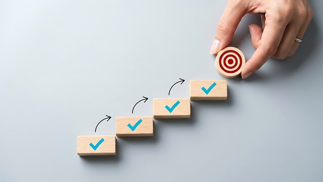 Business hand placing target round wooden block at top of staircase for strategic goal achievement