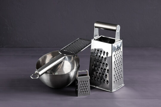 Cooking preparation and culinary tools, stainless steel kitchen graters and mixing bowl for food processing and meal prep on a dark wooden surface