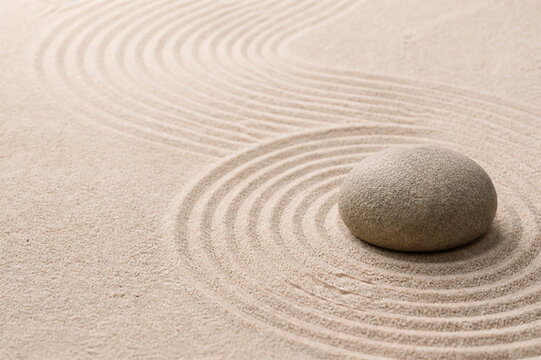 Single smooth stone on raked sand in a zen rock garden