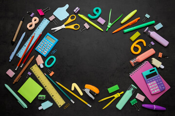 Back to school education concept, colorful stationery supplies arranged in a circle on a black chalkboard background with copy space for text © Pixel-Shot