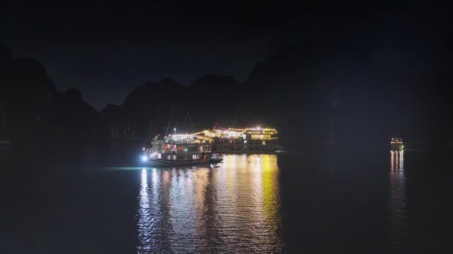 Night view of illuminated cruise ships anchored in Ha Long Bay, Vietnam, at dusk with dramatic sunset clouds and limestone karsts