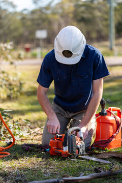 young tradesman apprentice refilling chainsaw fuel