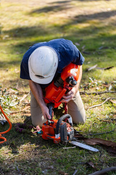 young tradesman apprentice refilling chainsaw fuel