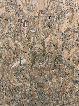 Vertical photo of a textured oriented strand board (OSB) panel showing compressed wood chips and flakes. Perfect for construction, building materials, interior design, manufacturing, and industrial
