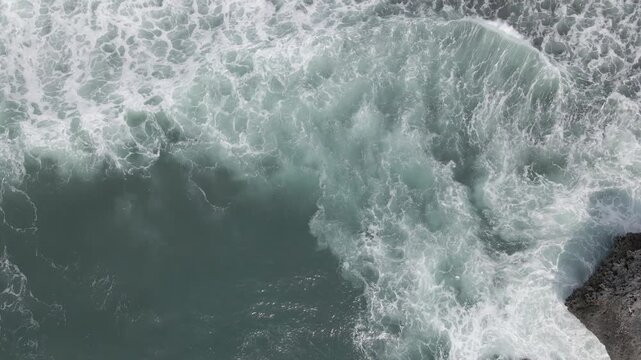Aerial top down view of powerful ocean waves crashing with white sea foam