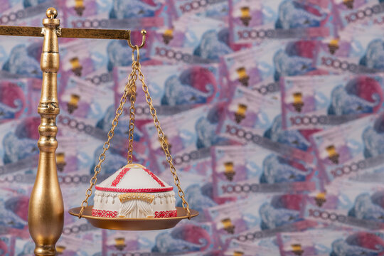 A symbolic Kazakh yurt resting on a scale against a background of 10,000 Kazakhstani tenge banknotes.
