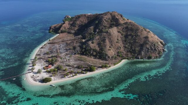 Kecamatan Komodo, Nusa Tenggara Timur, Indonesia - 09 September 2026: Aerial view of Kanawa Island surrounded by turquoise coral reefs and clear blue waters.