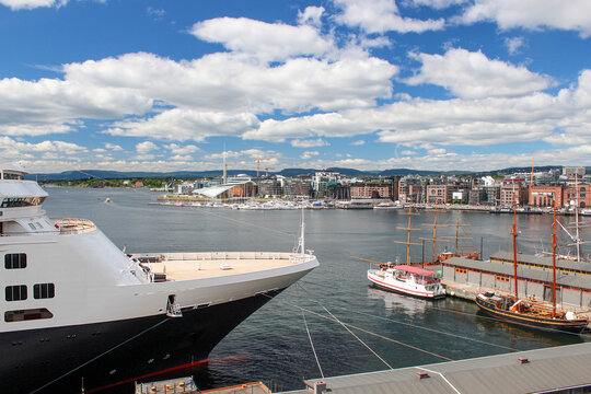 Luxury cruise ship travel and harbor port concept, large passenger liner docked at urban seaport with historical sailboats under cloudy sky, representing maritime tourism, and ocean voyage.