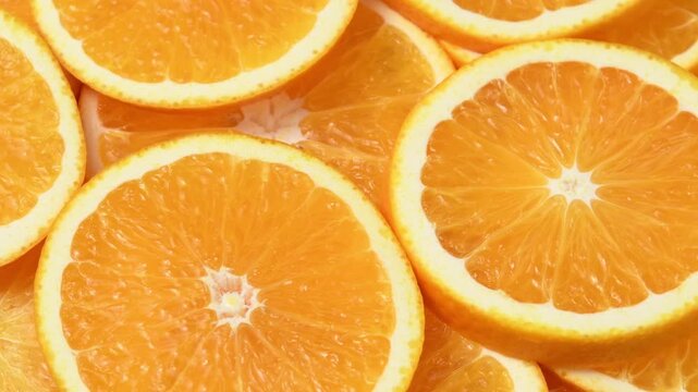 Overhead orange slices rotate in a horizontal frame, showing juicy citrus flesh and fresh texture.