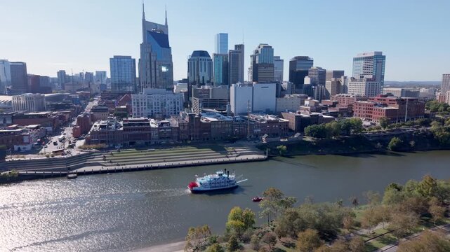 Nashville, TN, United States - 03 November 2025: Aerial view of the downtown skyline featuring the ATT Building and a riverboat cruising on the Cumberland River.