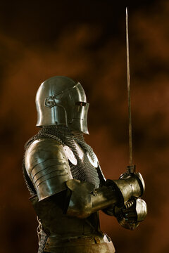 Vertical shot of medieval warrior wearing steel armor holding sword in profile view. Imagery suited for historical gaming, fantasy book covers, marketing campaigns