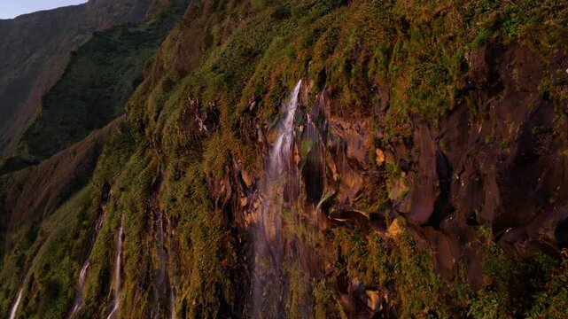 Po&ccedil;o da Ribeira do Ferreiro Lush Green Cliffs And Cascading Waterfalls At Sunset On Flores Island, Azores, Portugal. Aerial Approaching Shot