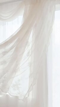 Soft white sheer curtains gently fluttering in a light breeze against a bright white background creating ethereal waving fabric textures