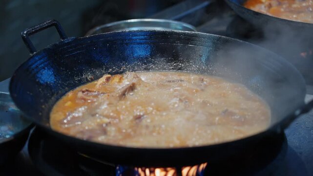 Cantonese dish Drunken Goose is cooked in a large iron pot over an open fire at a night market stall