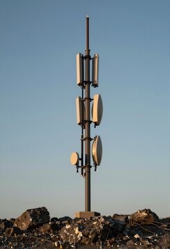 Isolated communications relay station on a windswept hilltop, guy wires anchoring the mast, golden hour light