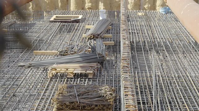 Symmetrical lines of rebar mesh create fascinating geometric texture. Bundles of steel materials await placement by construction crew