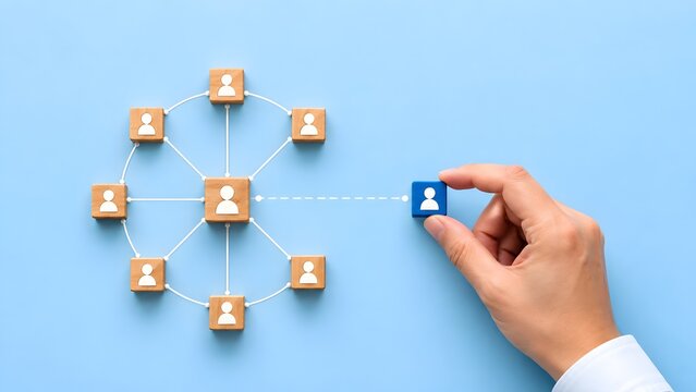 Hand placing blue block into connected network of wooden human icons for recruitment and team expansion