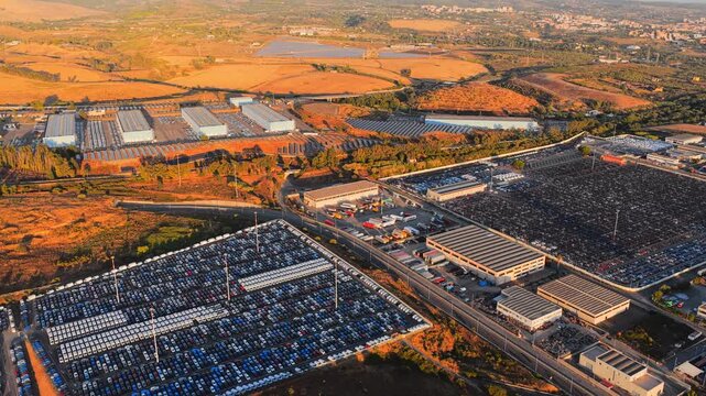 Aerial view of the extensive automotive storage facility at Civitavecchia Port with thousands of parked cars under golden hour light in Civitavecchia, Lazio, Italy.