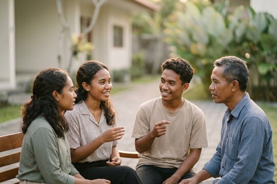 Southeast Asian Family Lifestyle Portrait involving Father and Adult Children Engaged in Conversation within a Lush Garden Courtyard for Community or Wellness Marketing Campaigns
