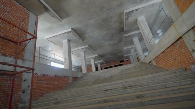 Structure appears under construction with visible scaffolding on right side. Orange brickwork contrasts with grey construction materials