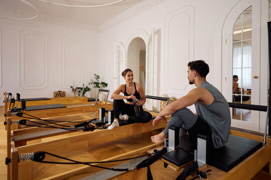 Athletic friends talking during water break in Pilates studio.