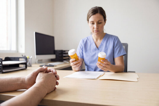 Clinician reviewing two medicine bottles with patient at desk