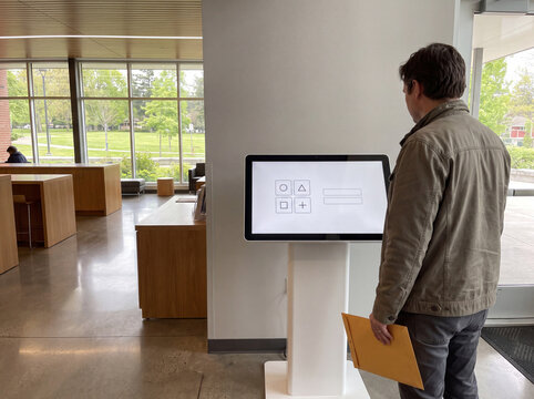 Visitor using self service touchscreen kiosk in public lobby