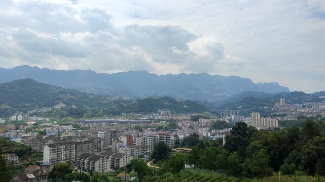 Panoramic view of mountain town surrounded by layered mountains and cloudy sky