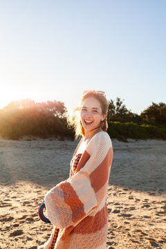 happy sunlit young woman at the beach with kite flying reel