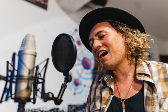 Independent music producer singing into studio microphone