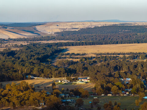 open cut coal mine on horizon seen over treetops from Bulga a small rural village