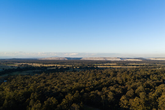 open cut coal mine on horizon in Hunter Valley seen over treetops from Bulga