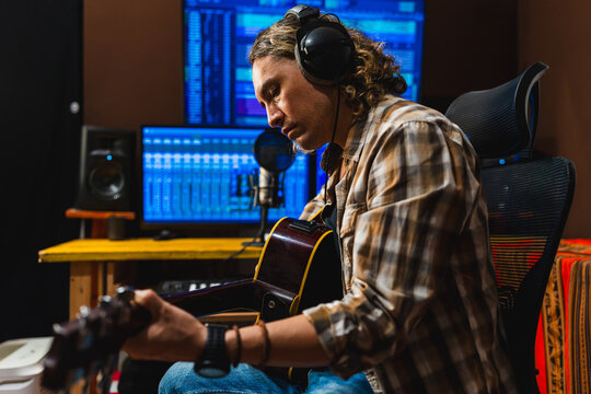 Male musician playing acoustic guitar in recording studio