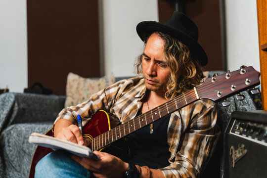 Songwriter composing music on acoustic guitar in studio