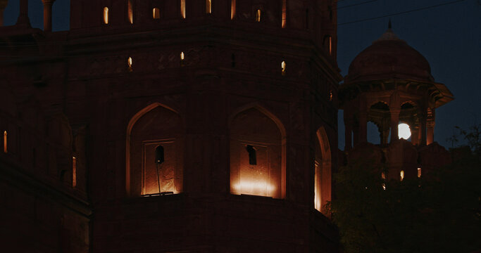 Full moon framed by arches of illuminated watchtower at Red Fort Delhi night scene