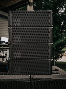 Stack of professional loudspeakers and sound equipment set up for an outdoor live music performance.