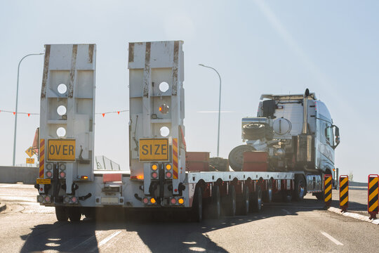 over size flatbed truck driving on narrow road crossing lanes in Australia