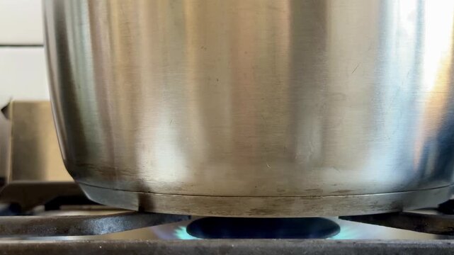 Stainless Steel Pot Heating on a Kitchen Gas Stove Hob Close Up