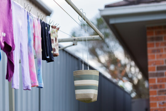 Striped peg basket bag hanging on washing line in Australian backyard