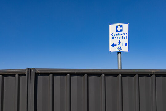 Sign for Canberra Hospital showing a bike and walking signal above a grey fence