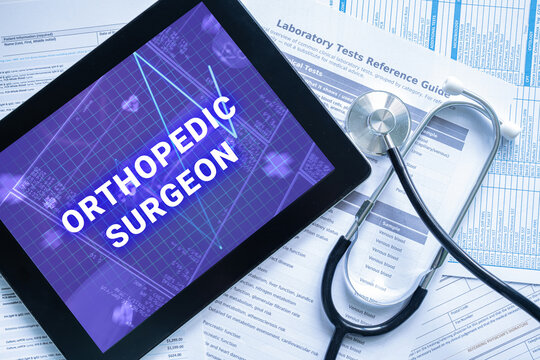 ORTHOPEDIC SURGEON text on digital tablet screen with stethoscope and documents, medical specialist healthcare concept