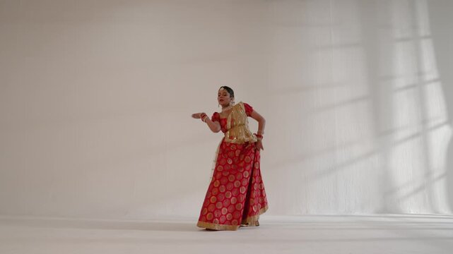 A woman  gracefully performing a classical Indian dance in a studio
