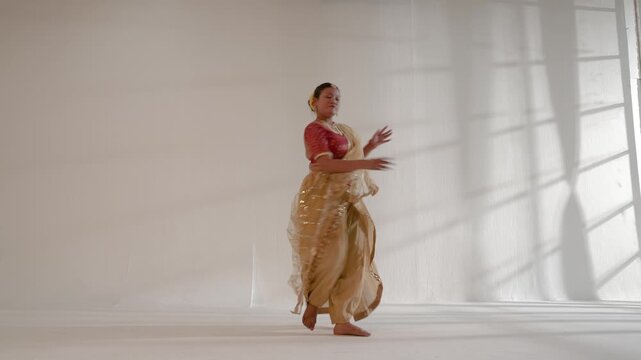 A woman  performing a classical Indian dance in a studio environment