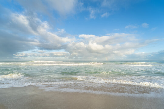 Foamy shore break waves on beach under soft clouds at Scarborough Beach, Perth, Western Australia