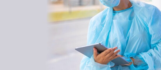 Doctor in blue surgical gown holding digital tablet, medical technology and healthcare concept © The DiTech