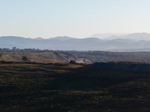 Layered mountains in the hazy distance with open cut coal mine in foreground