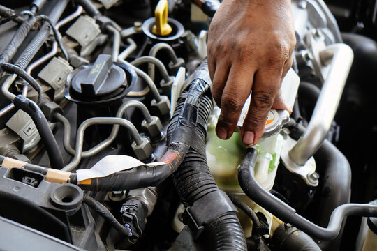 Mechanic hand performing maintenance by checking coolant reservoir in a car engine