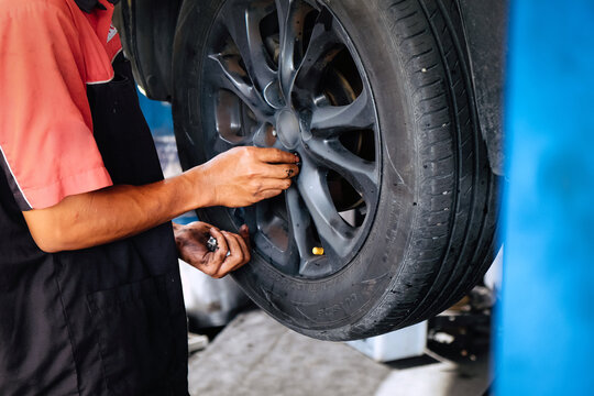 Mechanic working on a car wheel, removing lug nuts during tire change service